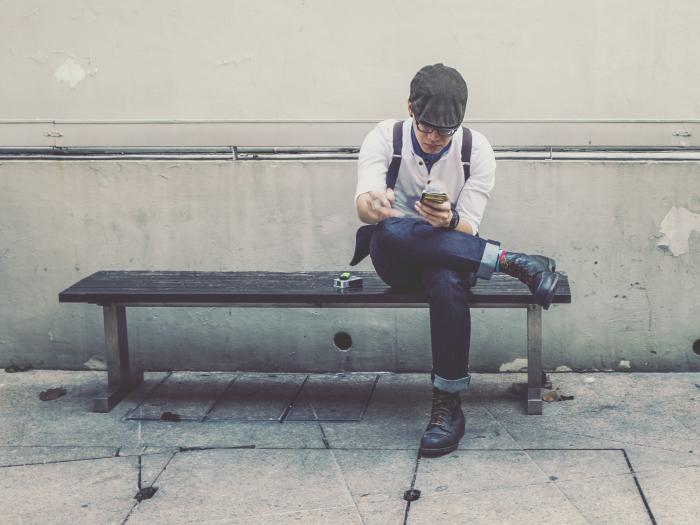 Man on bench with phone in hand. 